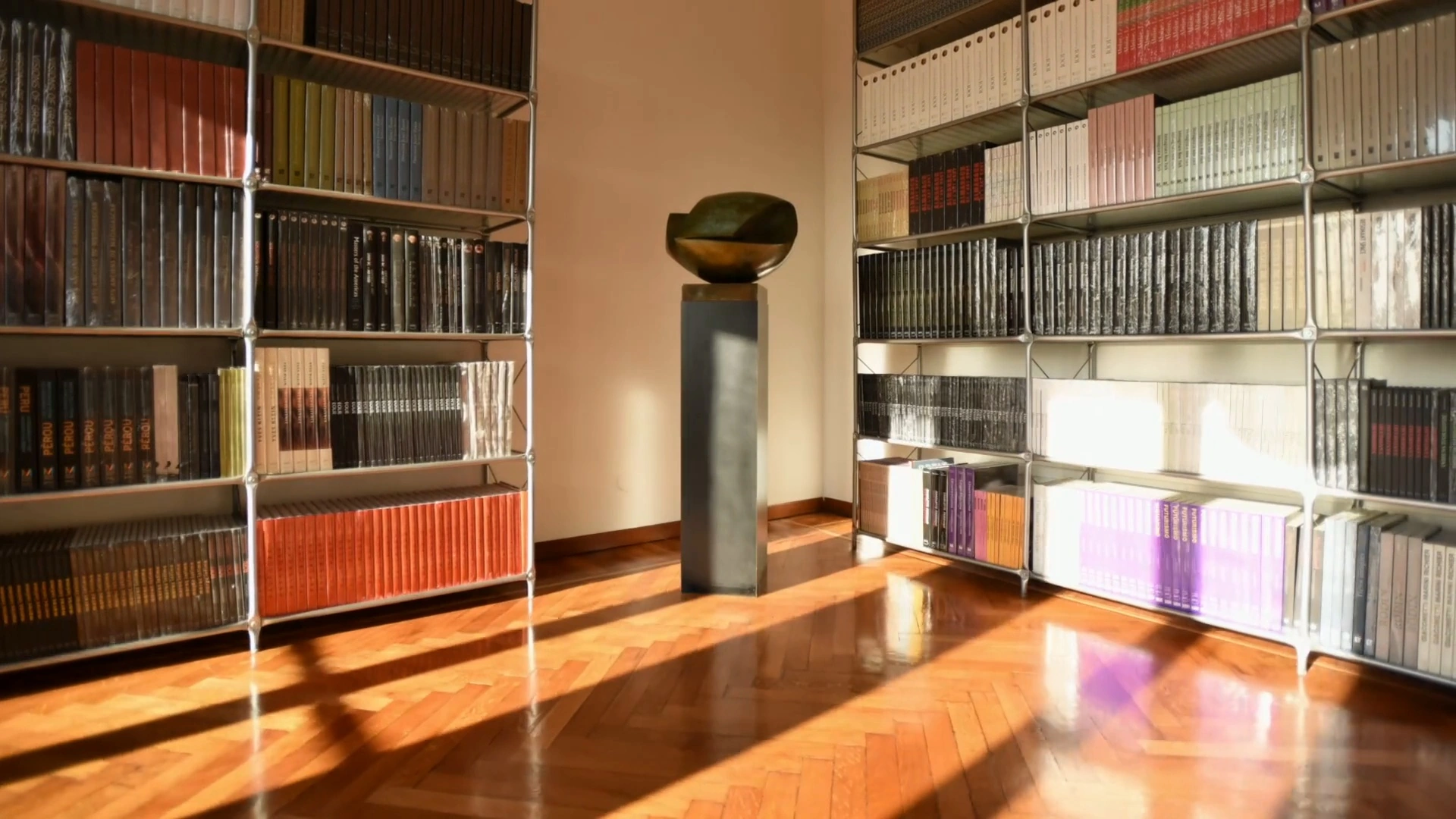 Sculpture between sunlit bookshelves