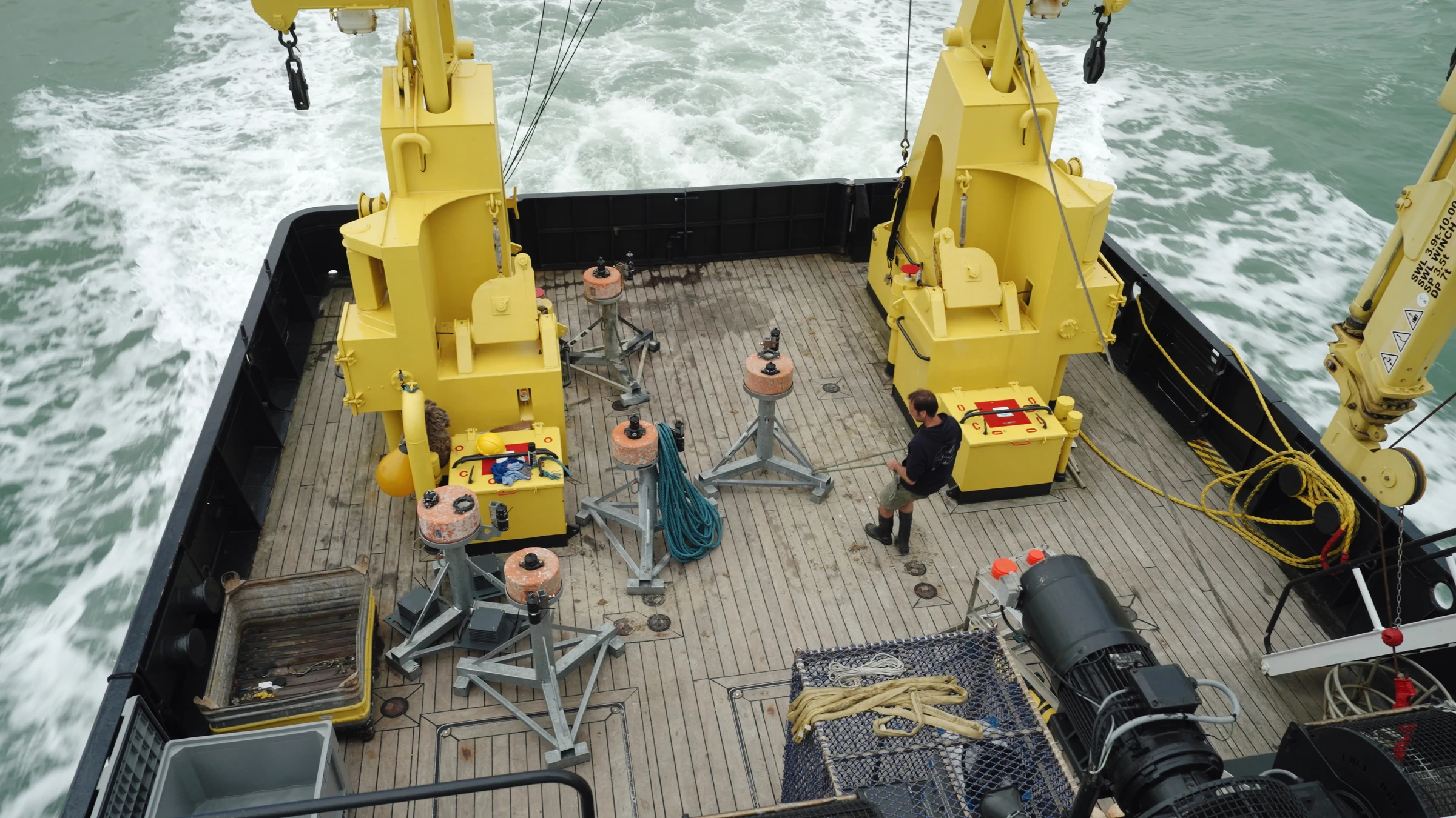 Research vessel deck with yellow cranes at sea