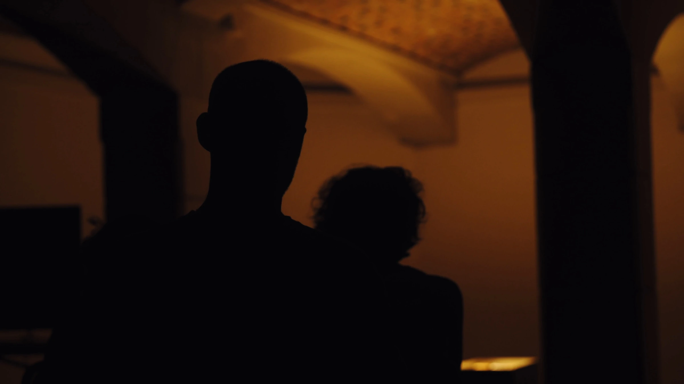 Visitors silhouetted in the warm exhibition light