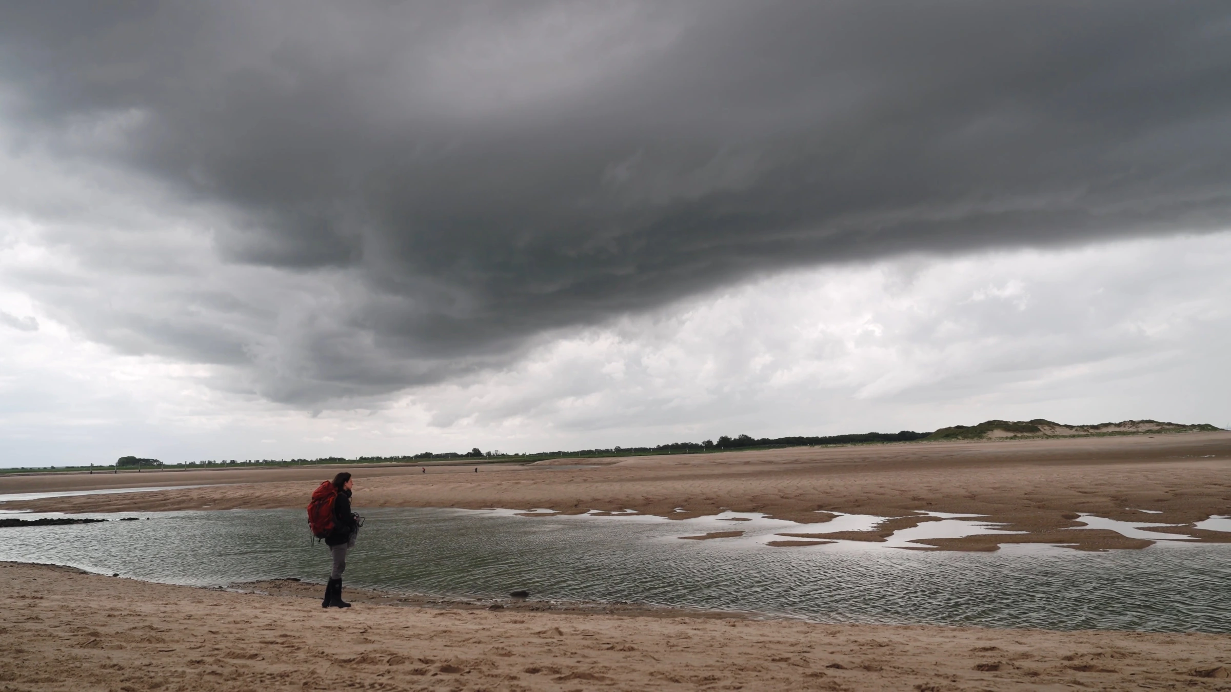 Elise on the beach beneath sweeping dark clouds