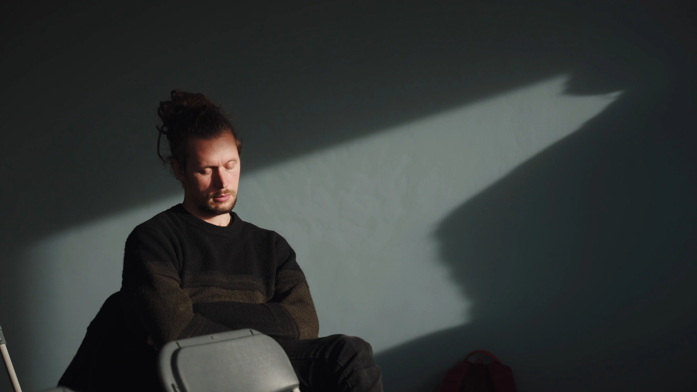 A man listening with eyes closed in a shaft of sunlight