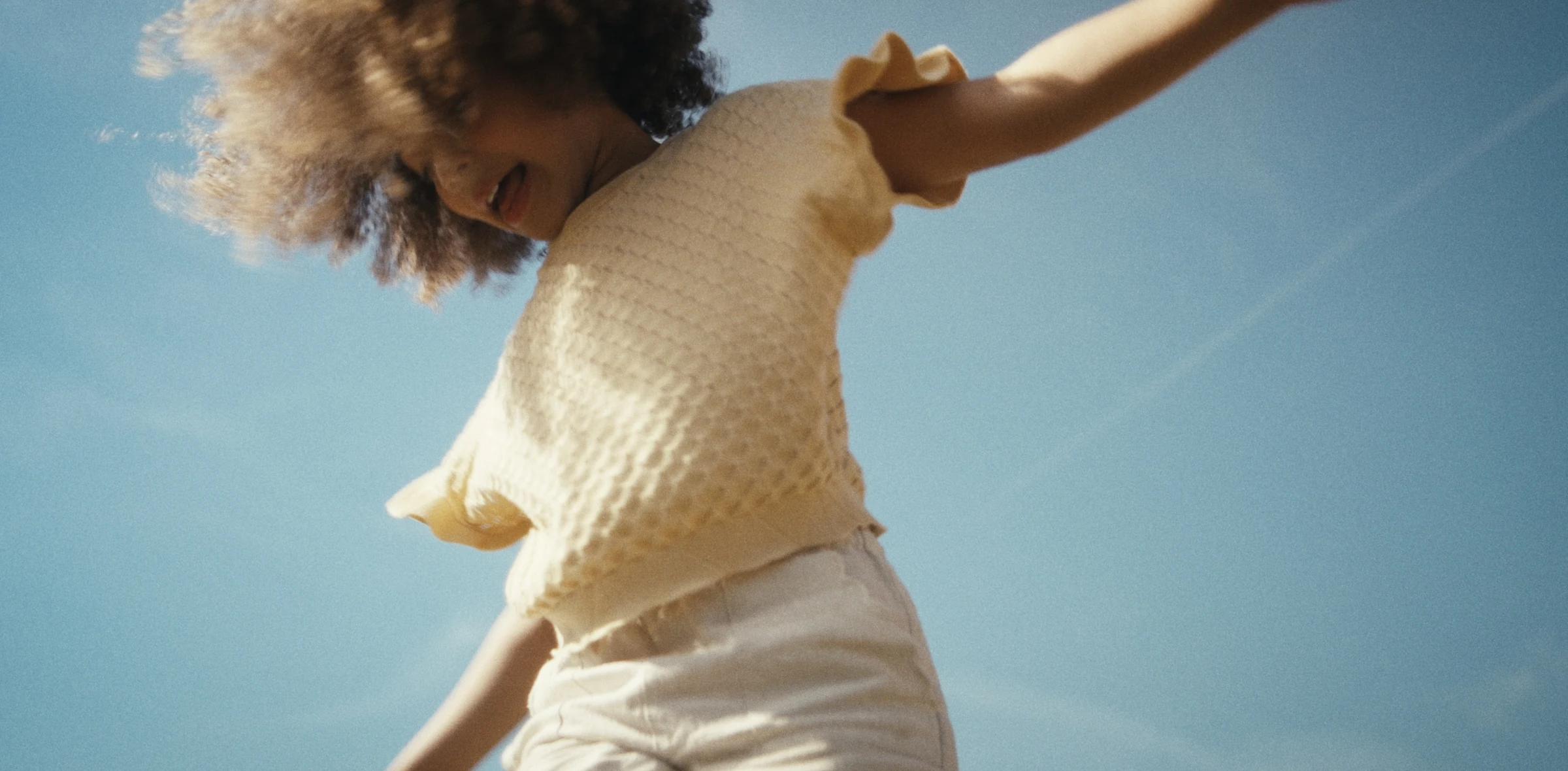 A child playing beneath a blue sky