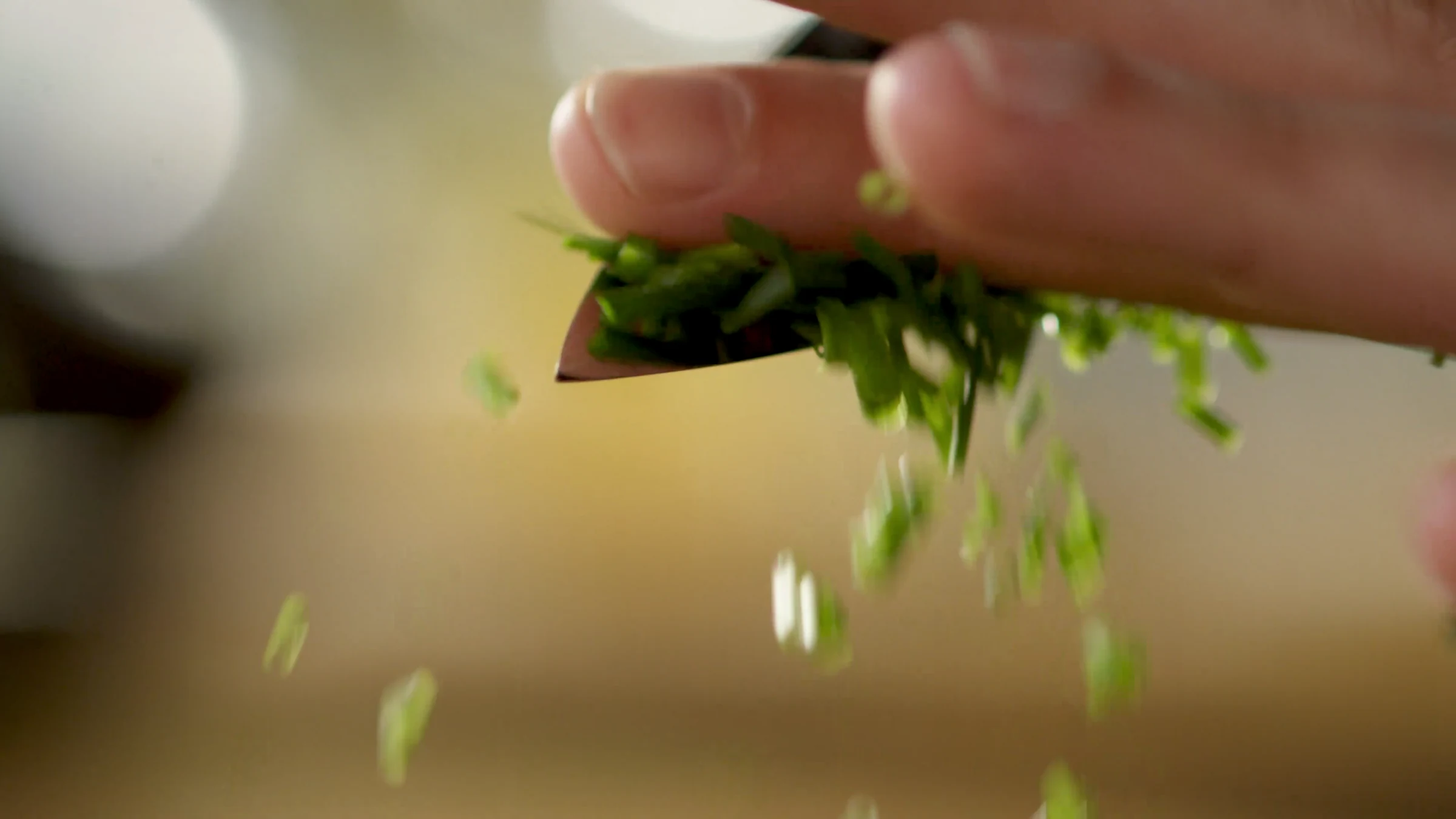 Fresh herbs falling from a knife