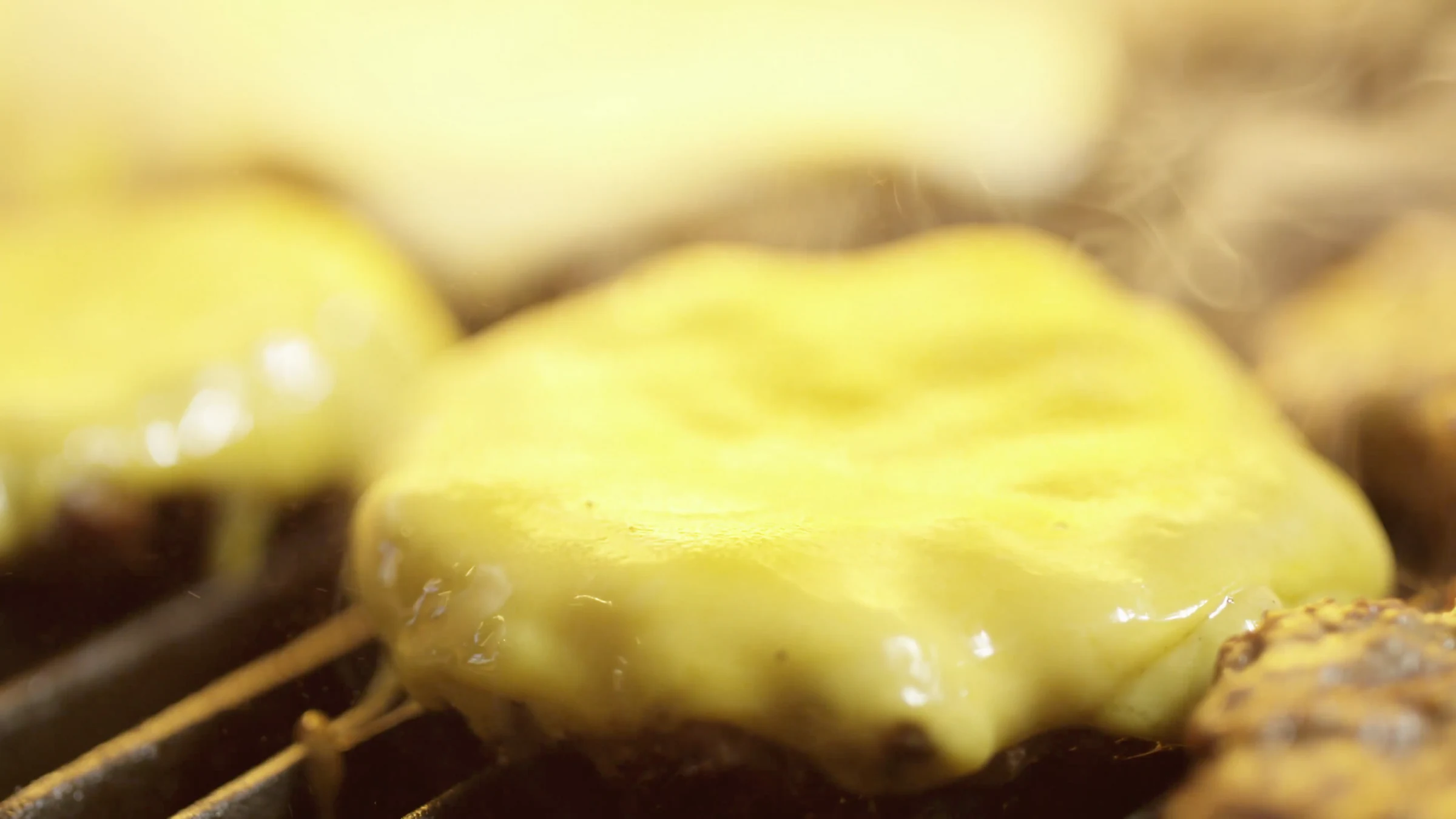 Cheese melting over a burger on the grill