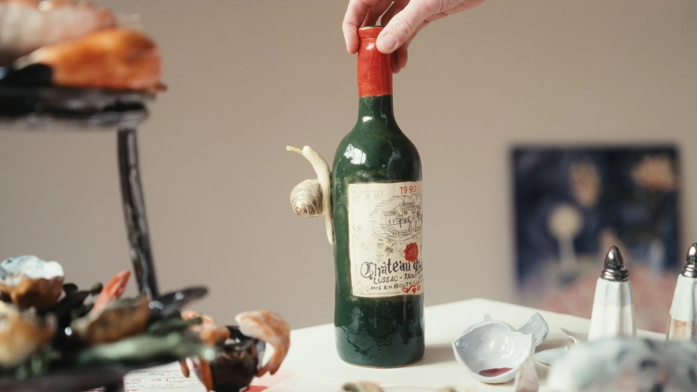 Hand lifting a ceramic wine bottle with a snail