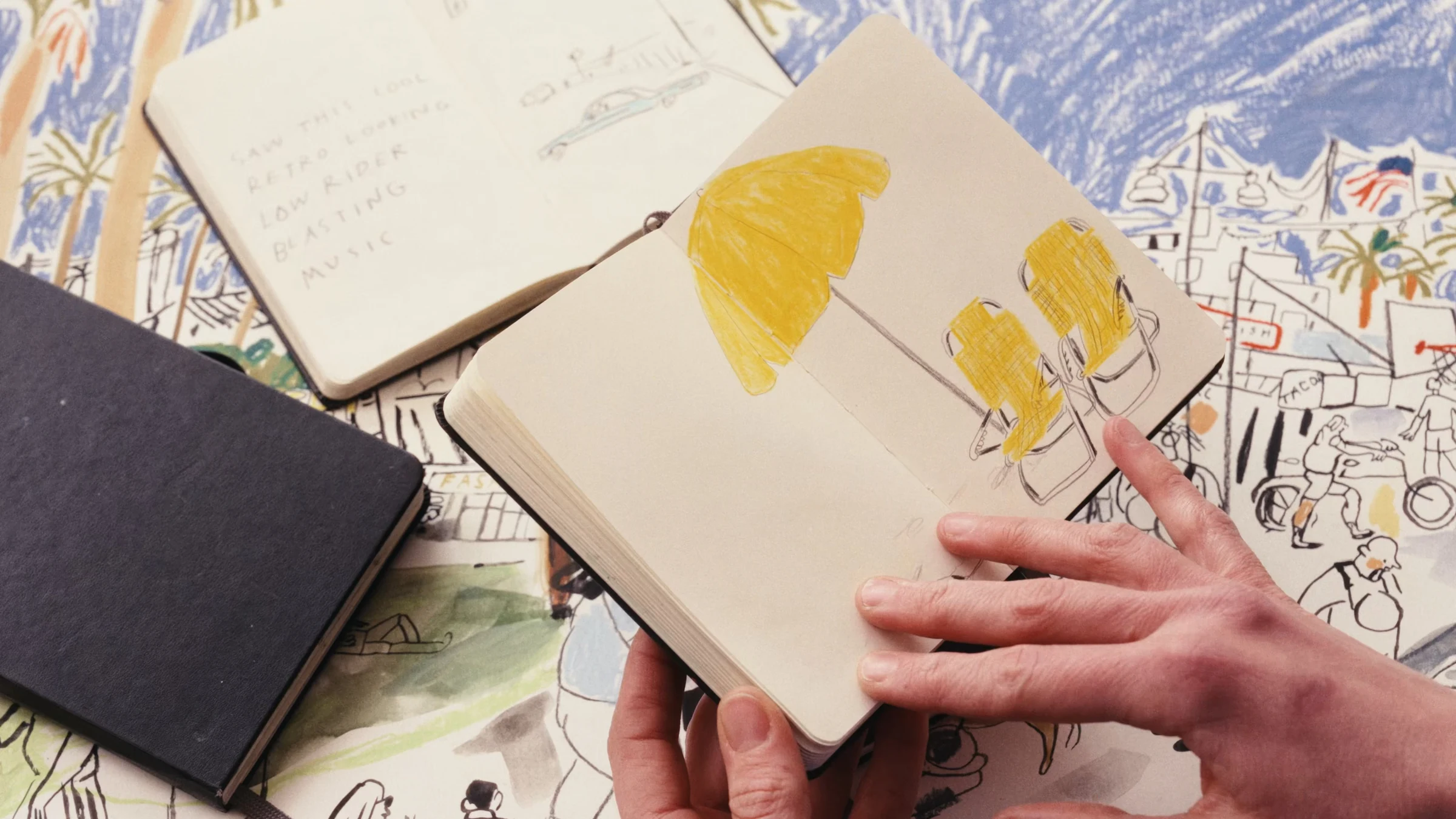 Open sketchbook with yellow chairs and a parasol