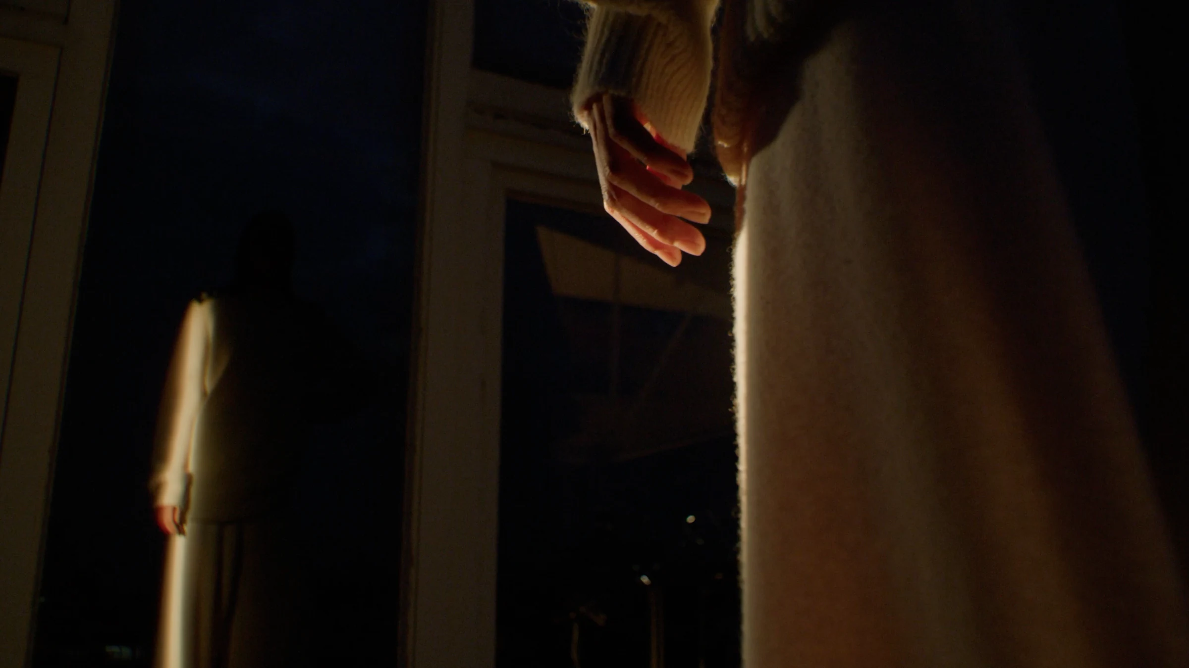 A hand and silhouette reflected in a mirror